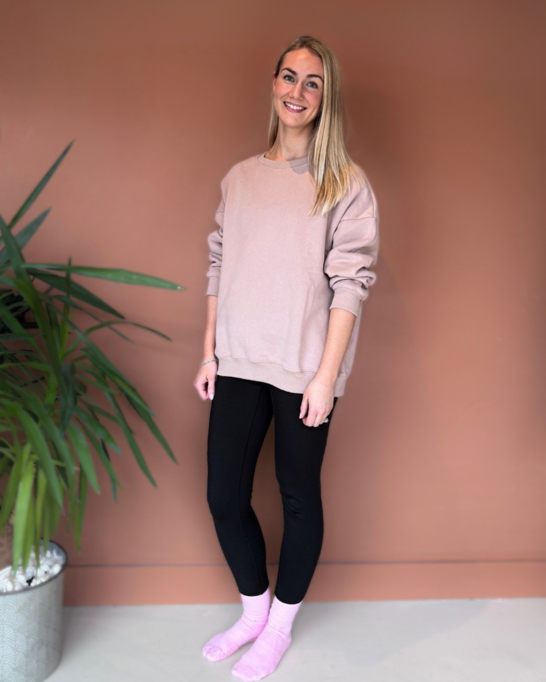 Grace wearing pink Grace Grips socks, black leggings and a blush sweatshirt